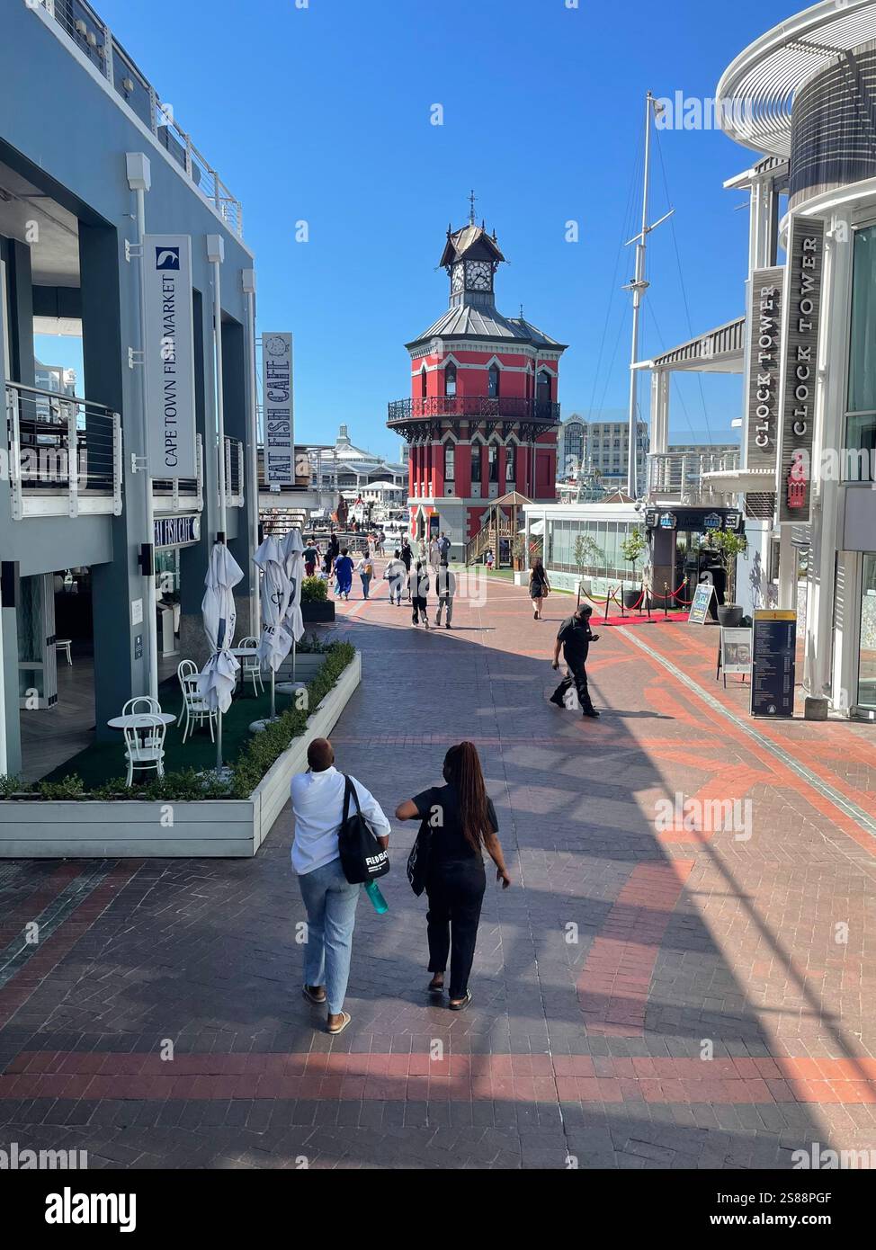 Clocktower at the V&A Waterfront, Cape Town viewed through restaurant buildings near the silo district during summer - Smartphone Captured Stock Image