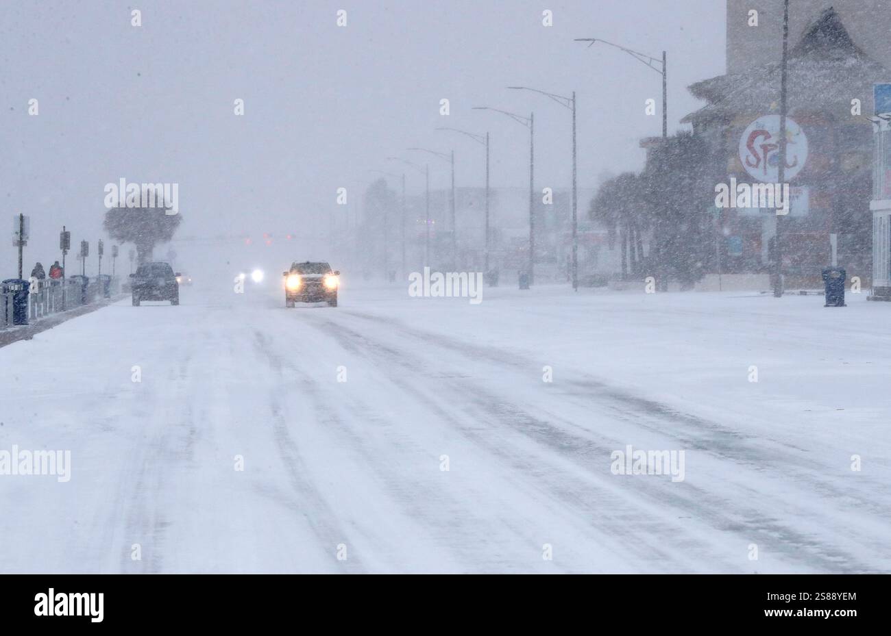 Drivers slowly make their way along Seawall Boulevard in Galveston, Texas during a snowstorm