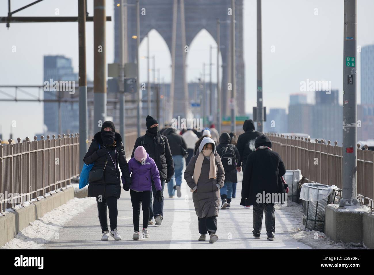 Bundled up pedestrians walk across the Brooklyn Bridge in New York, Tuesday, Jan. 21, 2025. (AP