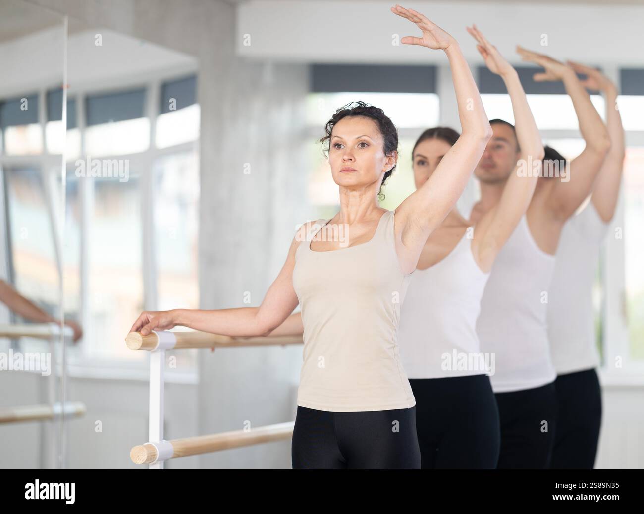Woman performing third ballet position in group barre workout Stock ...