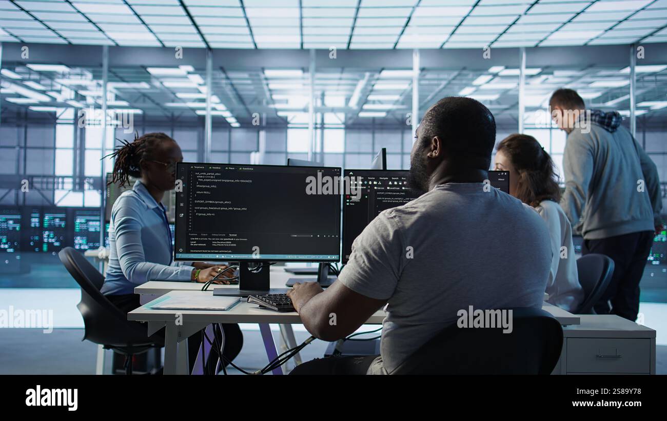 Admin programming in server room housing advanced equipment storing massive datasets. Developer typing code on PC to mend data center racks doing complex computational operations, camera B Stock Photo