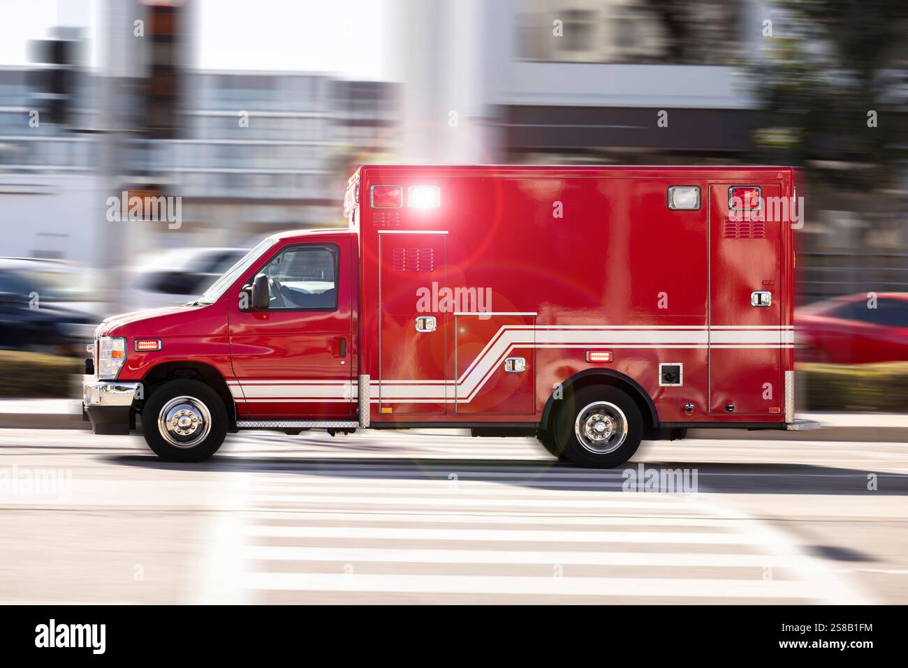 Motion panned view of an ambulance on a city street racing to the scene ...