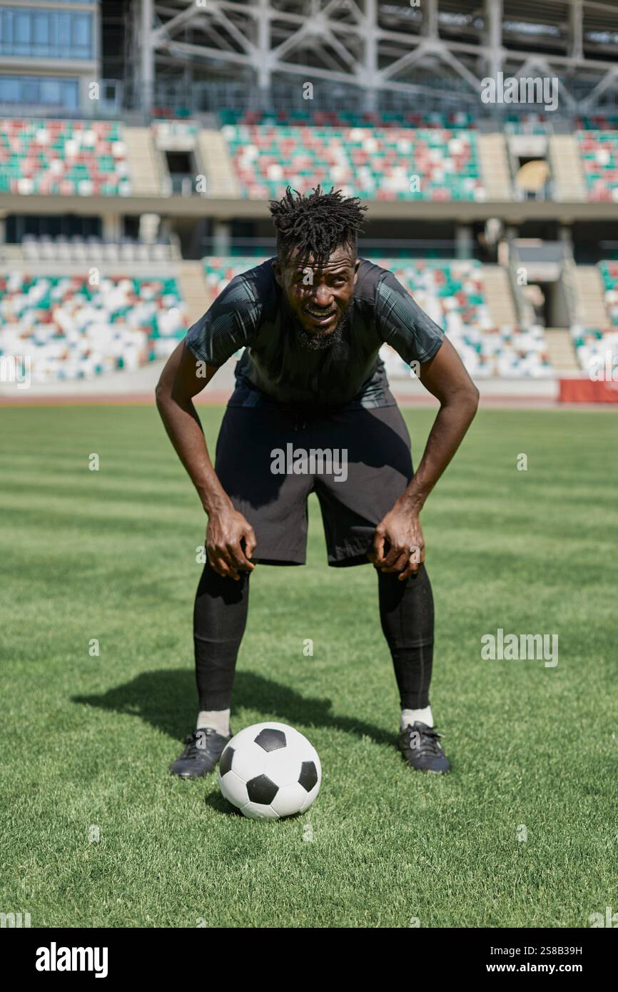 Confident young african american soccer player kicking ball in stadium ...