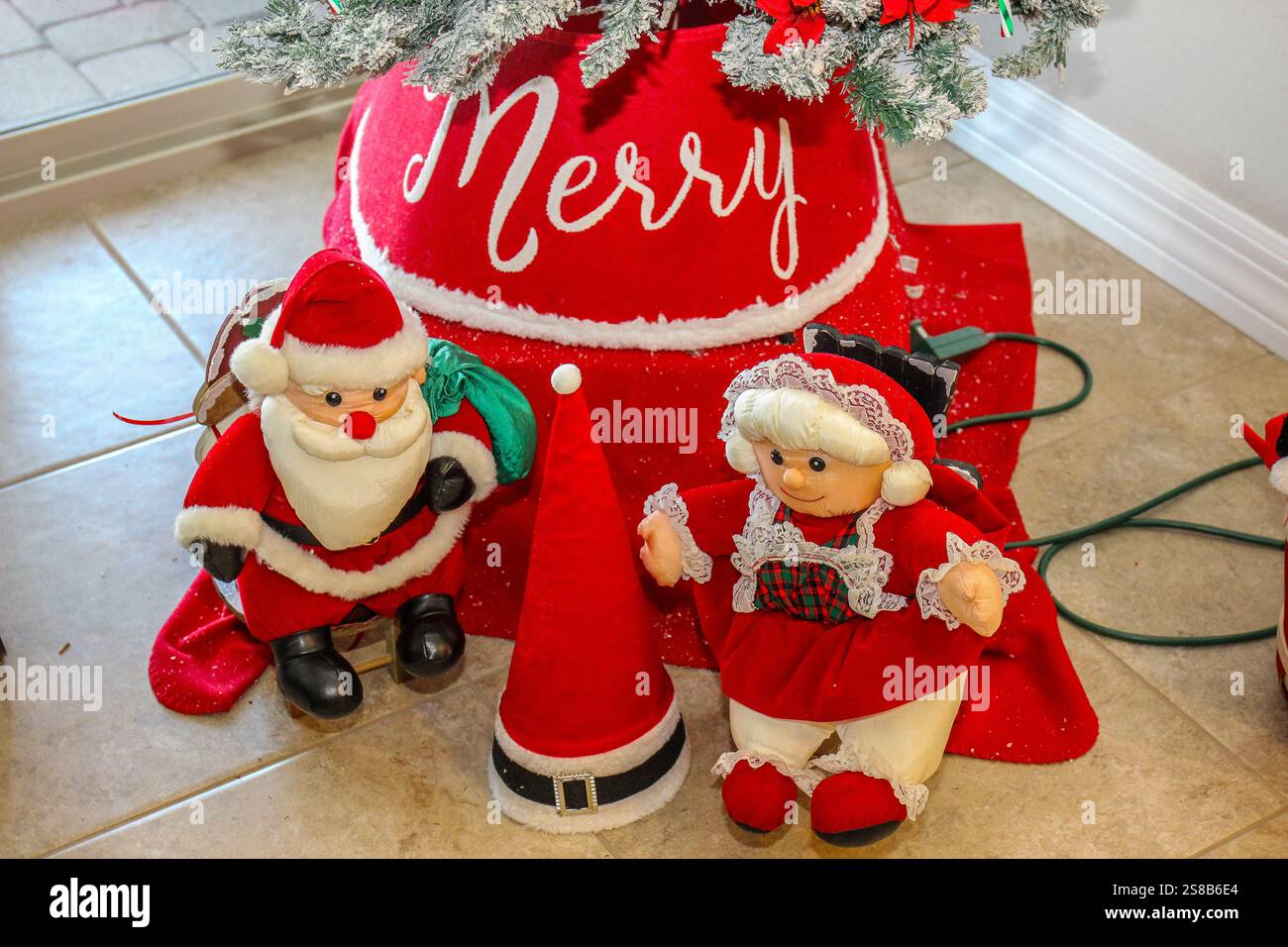 Small Mr. & Mrs. Santa Clause Sitting In Front Of Tree Stock Photo