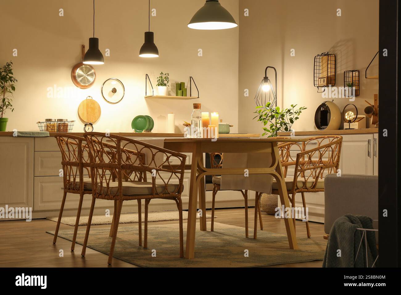 Interior of modern kitchen with glowing lamps, white counters, chairs ...