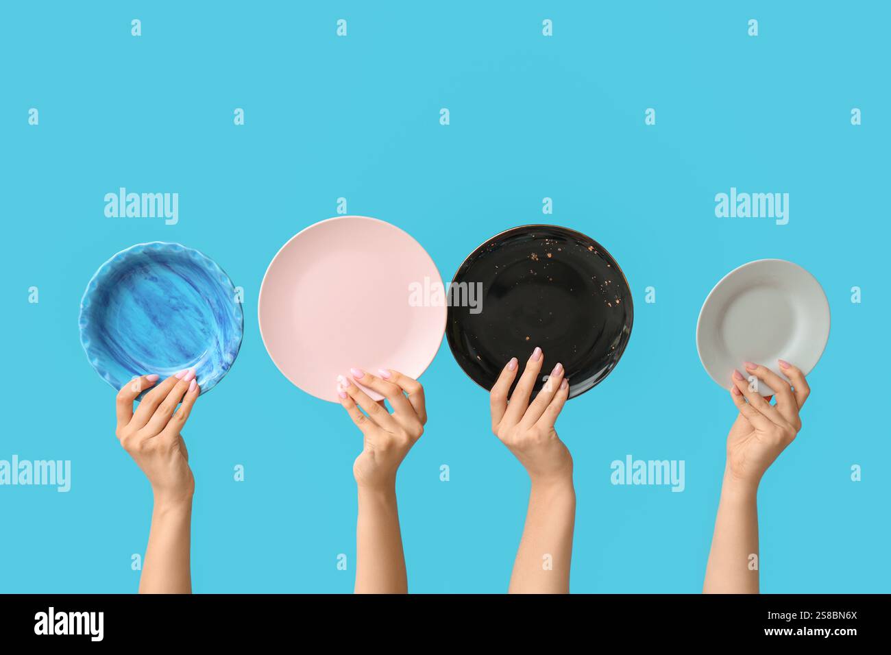 Hands holding empty plates on blue background Stock Photo