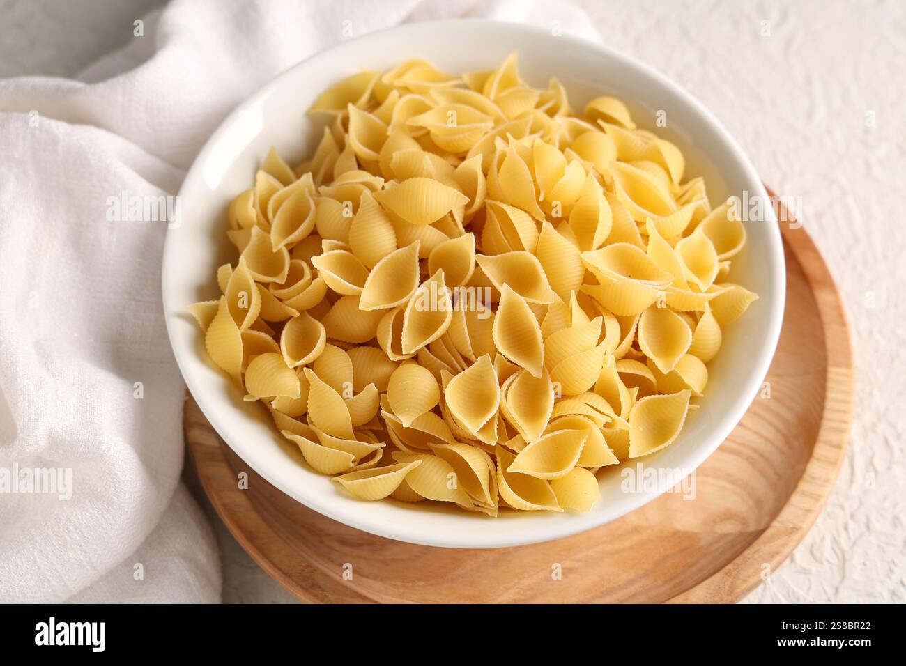 Bowl with raw pasta shells on white background Stock Photo - Alamy