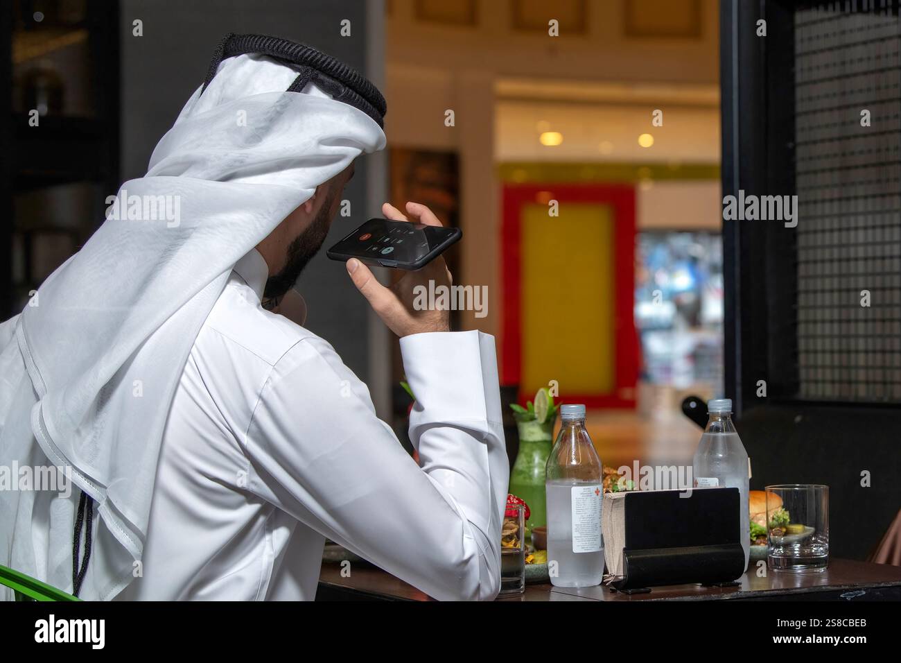 Young Arab Man holding phone in restaurant. back view Stock Photo
