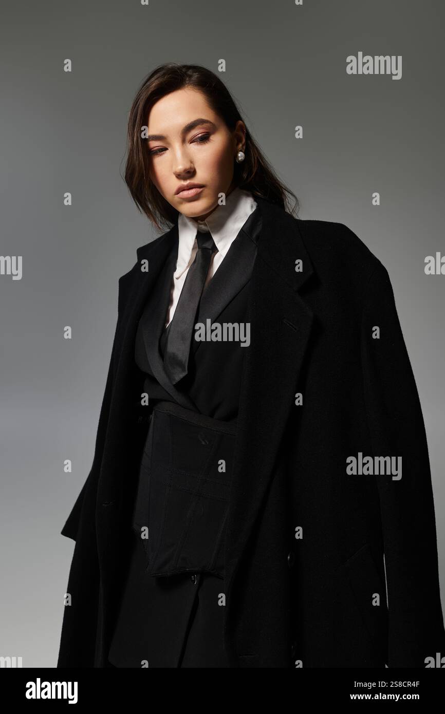 A young woman with long brown hair poses elegantly in a chic black ...