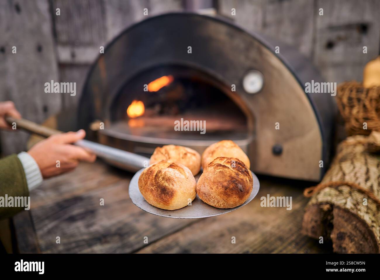 Cooking rustic bread rolls with fire at the Hidden Hut cafe at Porthcurnick Beach, Cornwall, UK Stock Photo