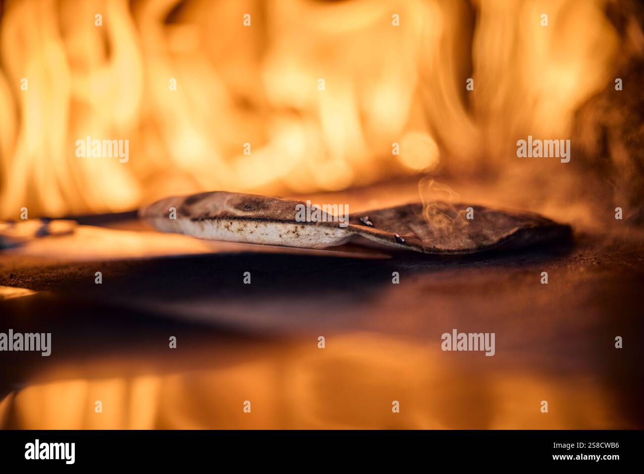 Cooking rustic flatbreads with fire at the Hidden Hut cafe at Porthcurnick Beach, Cornwall, UK Stock Photo
