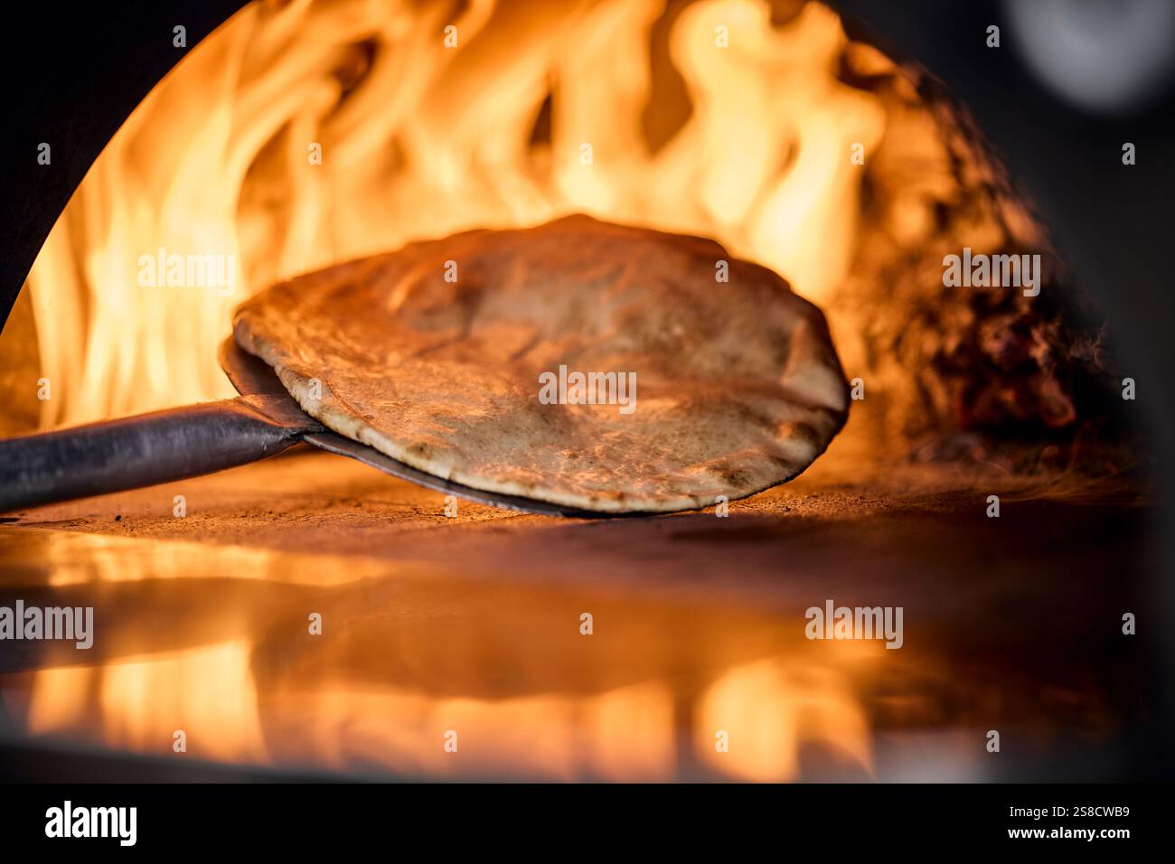 Cooking rustic flatbreads with fire at the Hidden Hut cafe at Porthcurnick Beach, Cornwall, UK Stock Photo