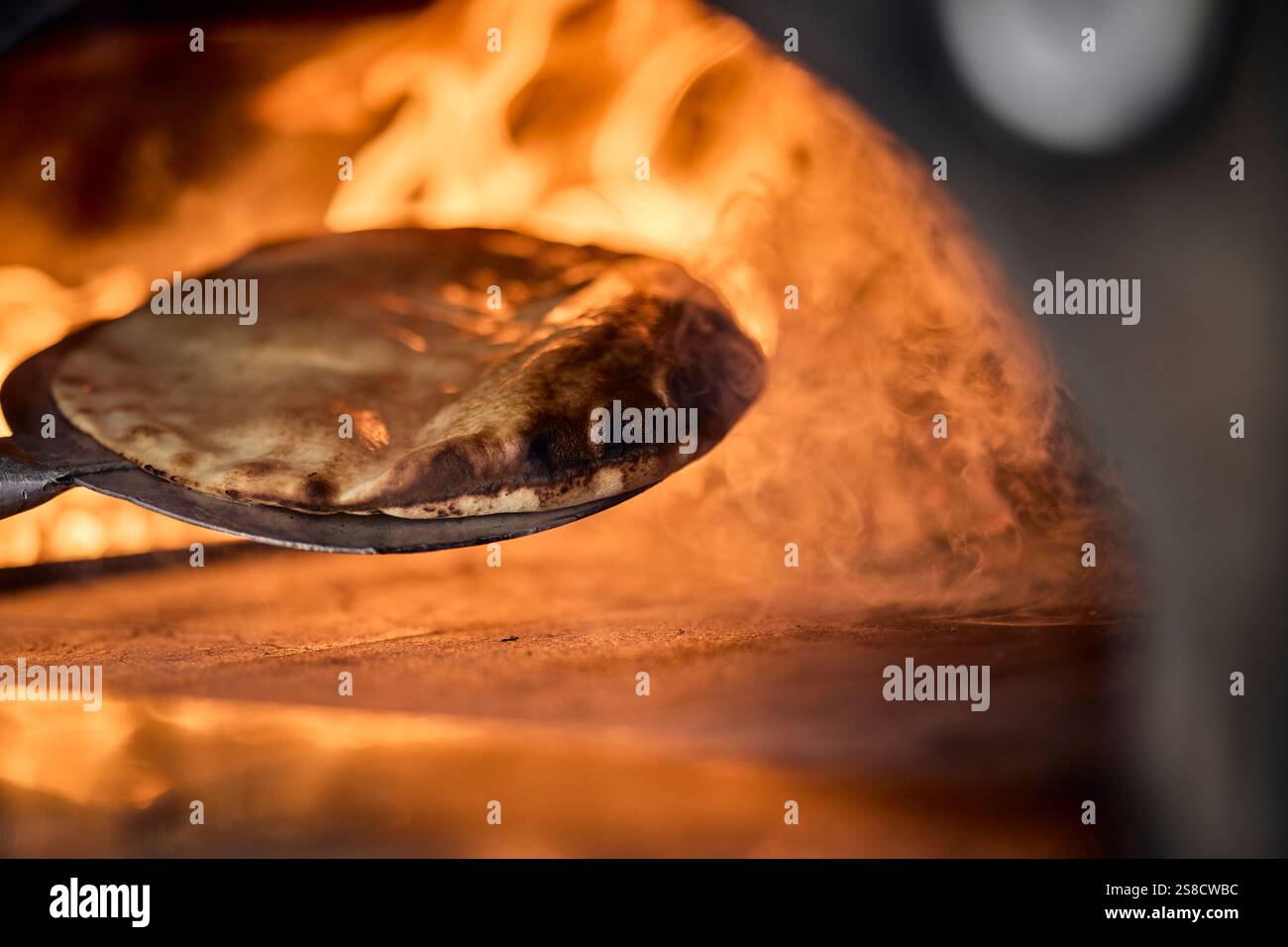Cooking rustic flatbreads with fire at the Hidden Hut cafe at Porthcurnick Beach, Cornwall, UK Stock Photo