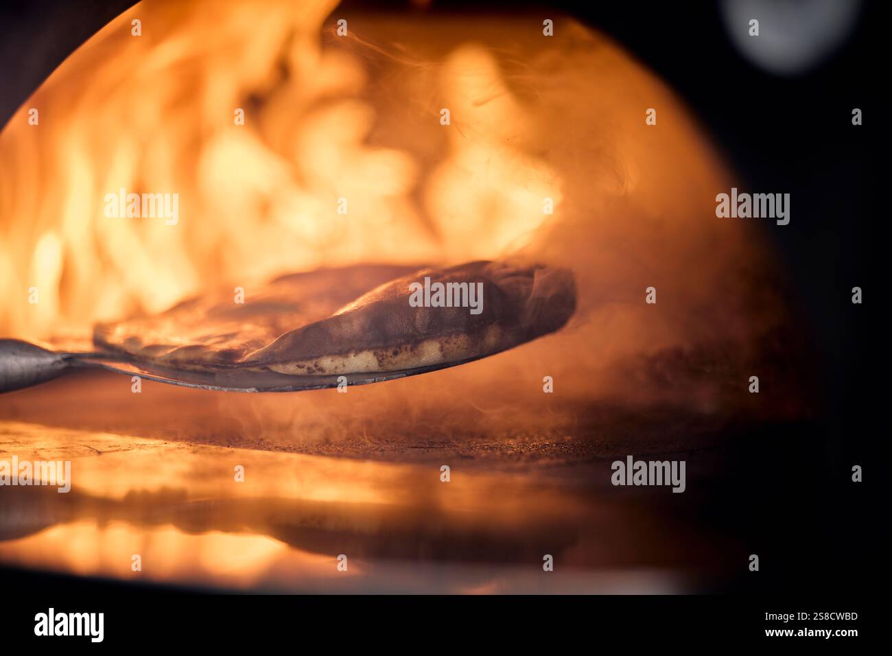 Cooking rustic flatbreads with fire at the Hidden Hut cafe at Porthcurnick Beach, Cornwall, UK Stock Photo
