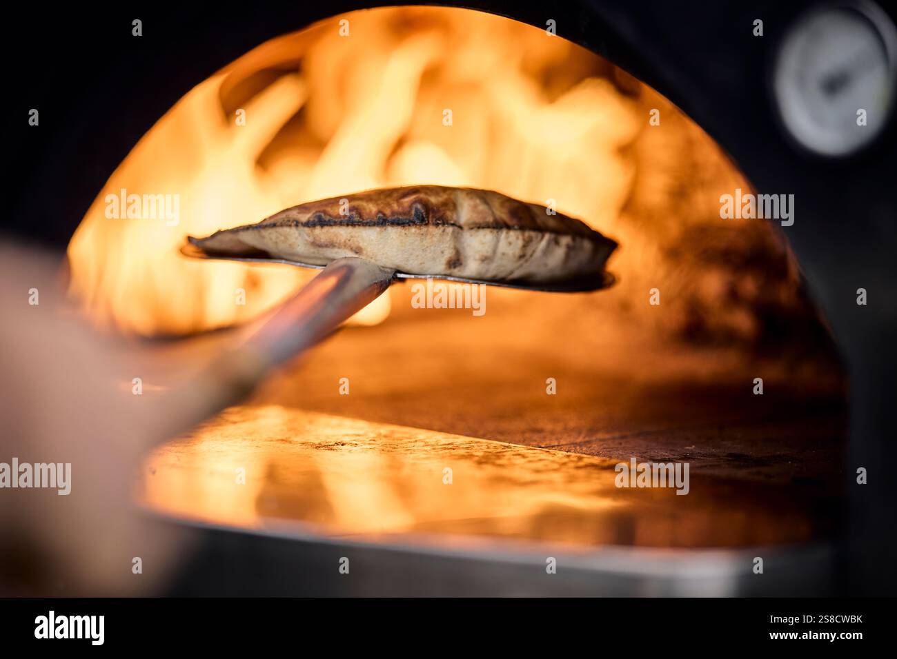 Cooking rustic flatbreads with fire at the Hidden Hut cafe at Porthcurnick Beach, Cornwall, UK Stock Photo