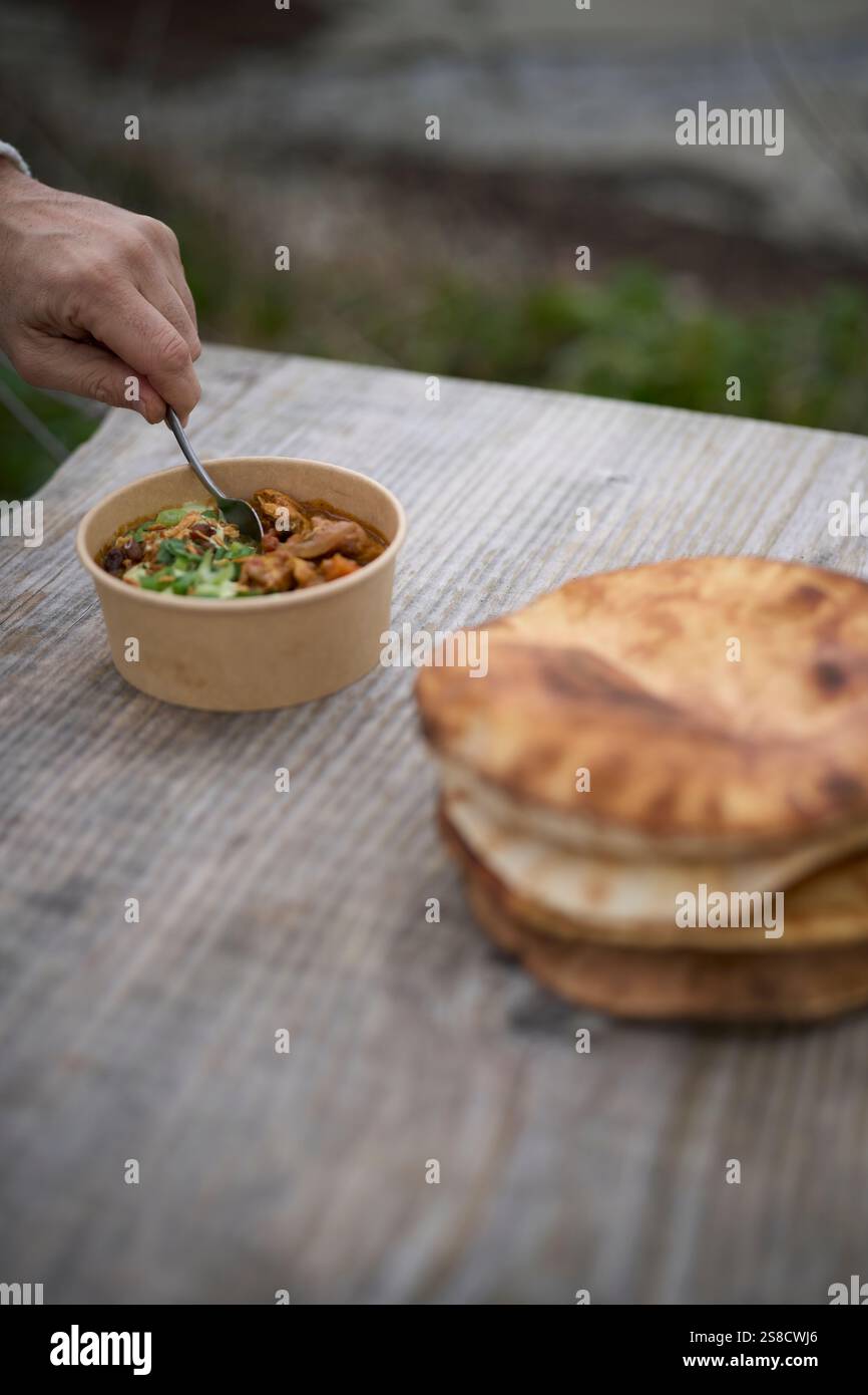 Winter spiced chicken soup and flatbreads cooked over fire at the Hidden Hut cafe at Porthcurnick Beach, Cornwall, UK Stock Photo