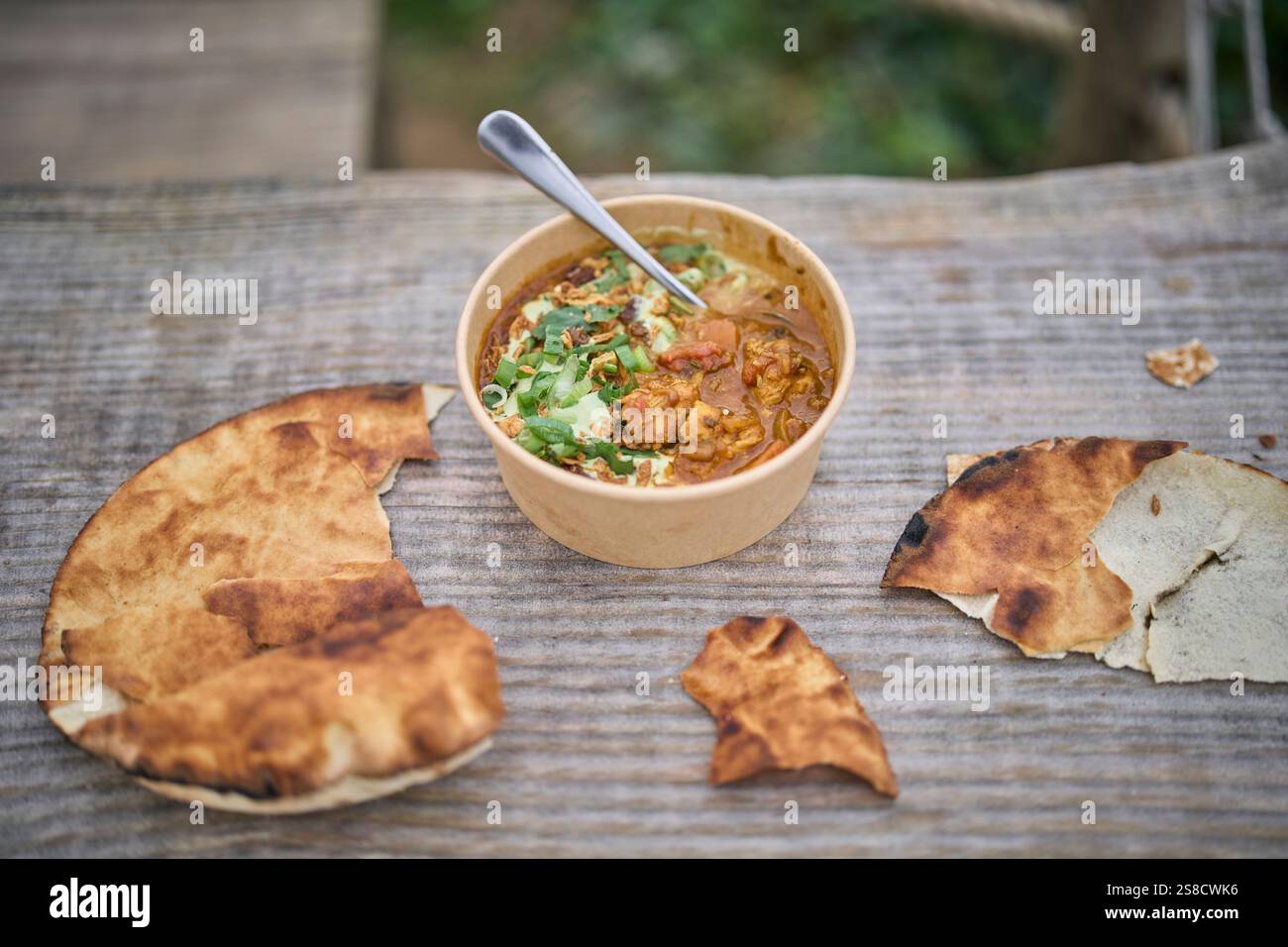 Winter spiced chicken soup and flatbreads cooked over fire at the Hidden Hut cafe at Porthcurnick Beach, Cornwall, UK Stock Photo