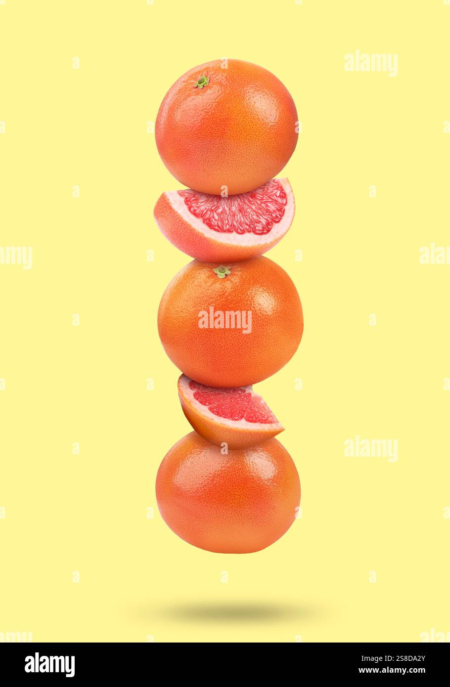 Fresh grapefruits in air on light yellow background Stock Photo