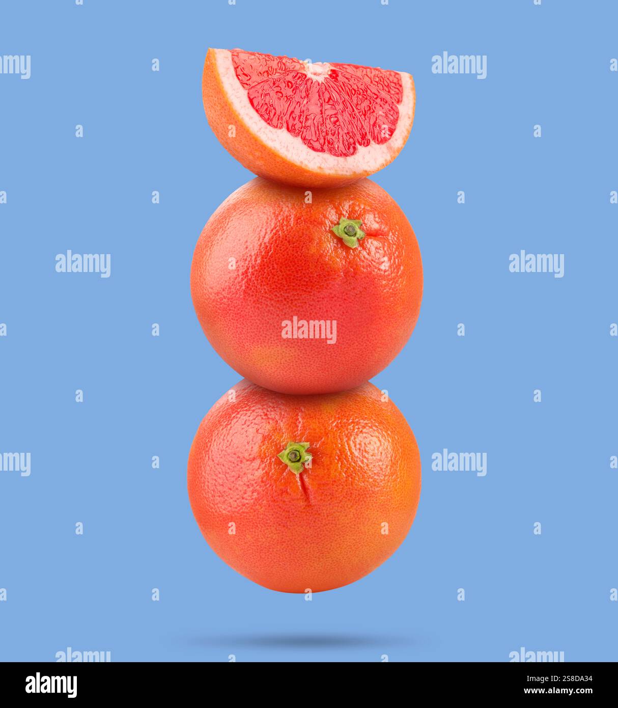 Fresh grapefruits in air on light blue background Stock Photo