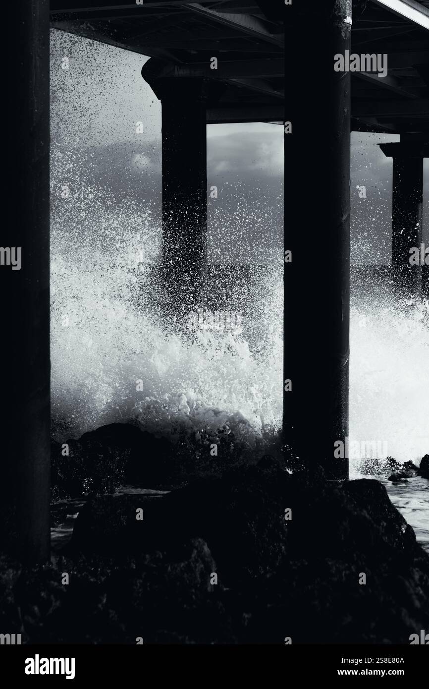 Black and white photo captures powerful waves crashing against a pier's ...