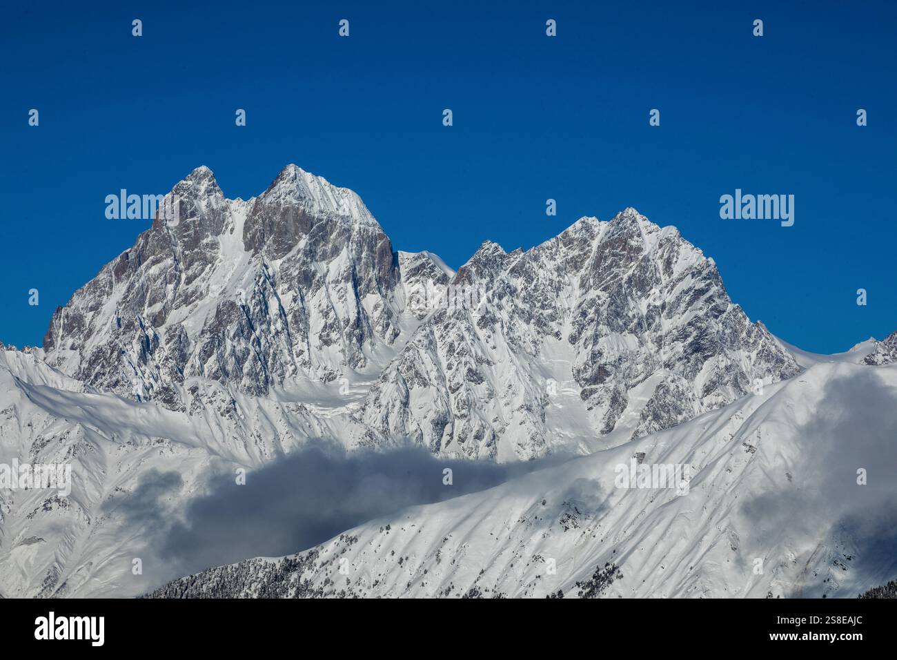 Majestic snow-covered mountain peaks tower under a clear blue sky ...