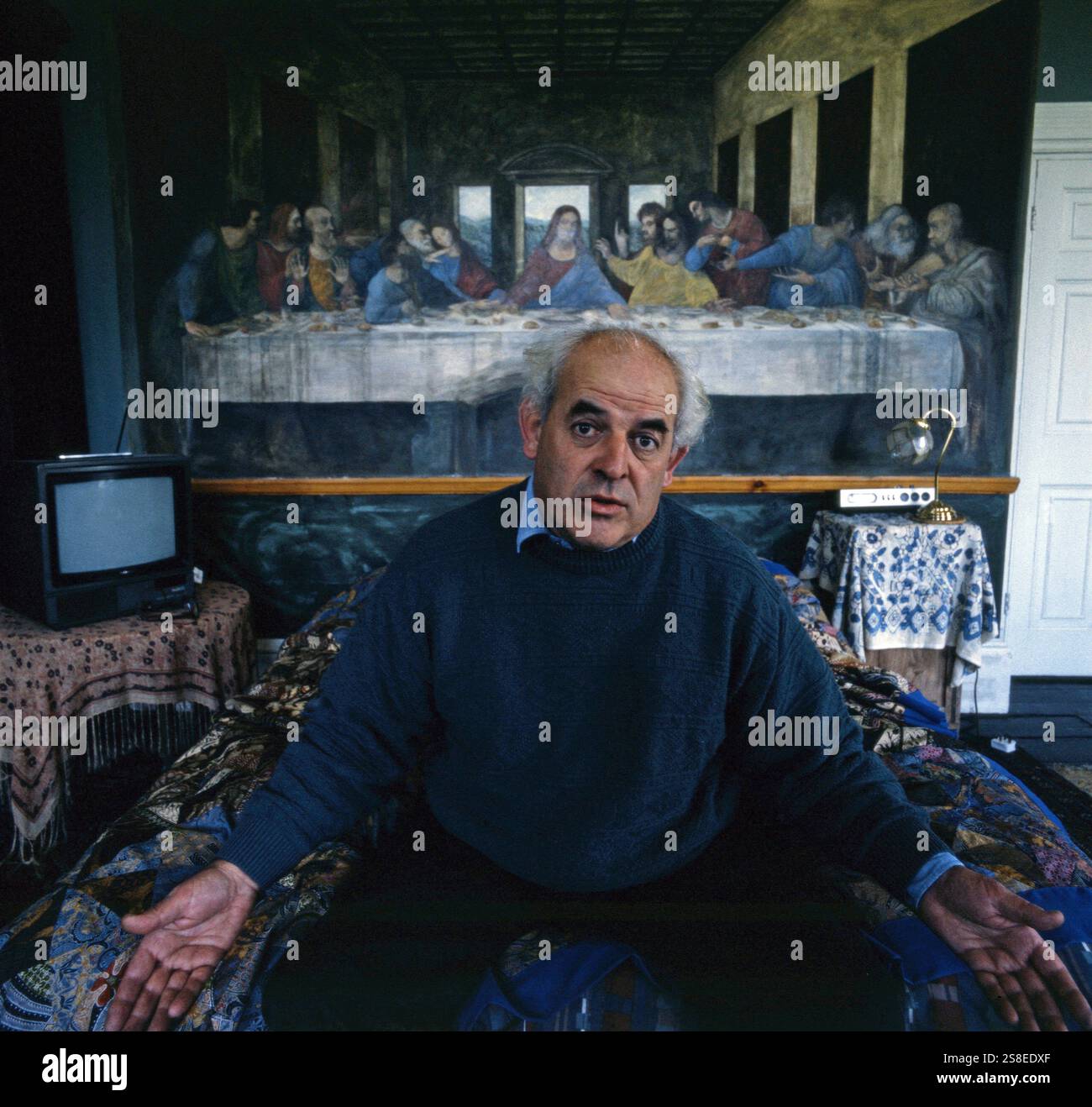 Portrait of Ralph Steadman cartoonist, painter, caricaturist  and draughtsman in front of his take of The Last Supper in his home in Loose, Kent circa 1994 Stock Photo
