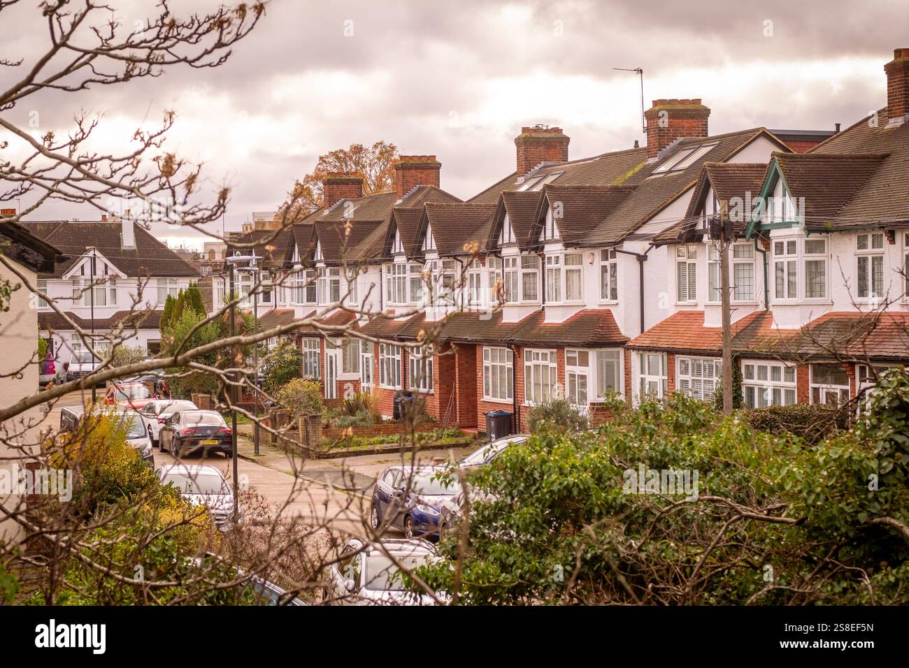 LONDON-  Row of terraced houses with bay windows and on street parking in Morden area of south west London Stock Photo