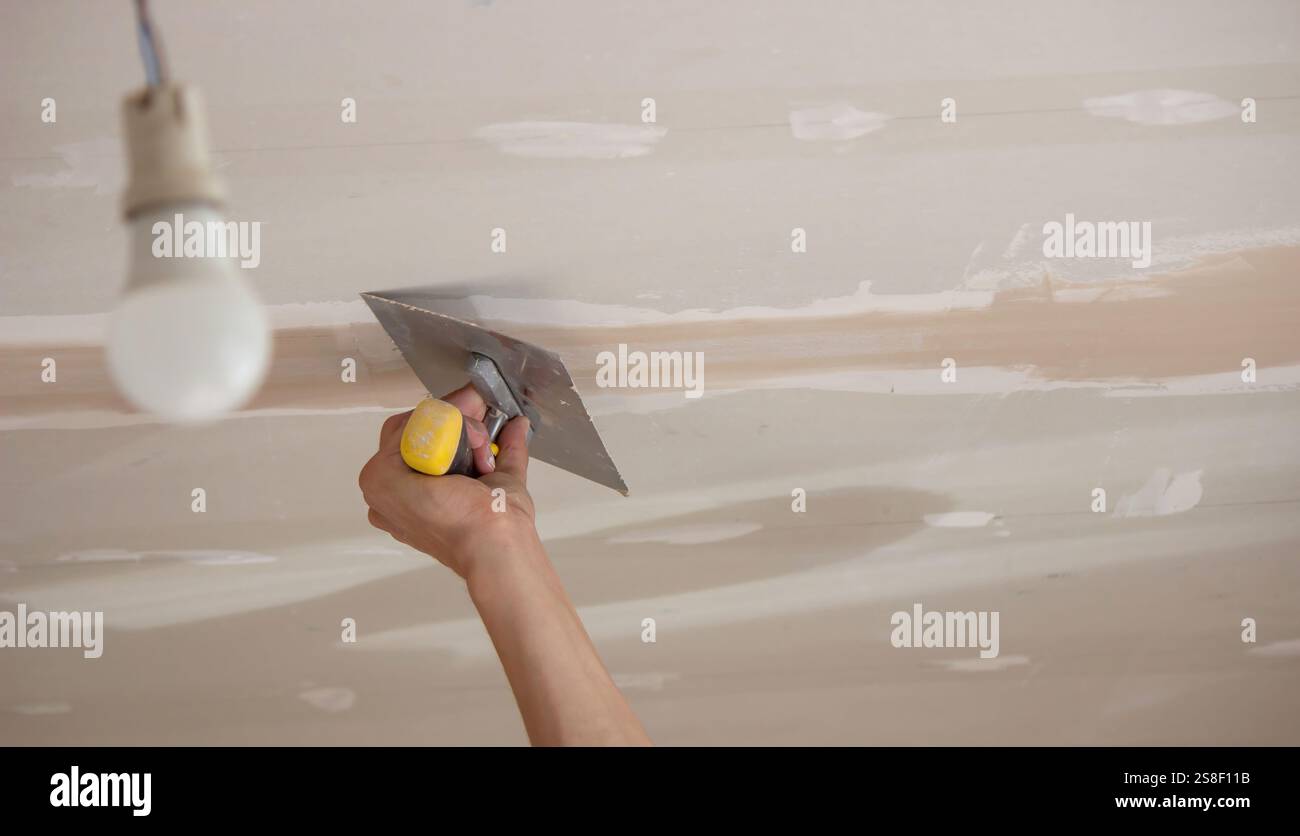 man plastering ceiling repair. Selective focus. Stock Photo