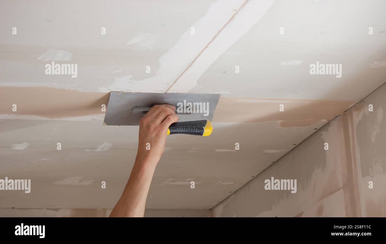 man plastering ceiling repair. Selective focus. Stock Photo