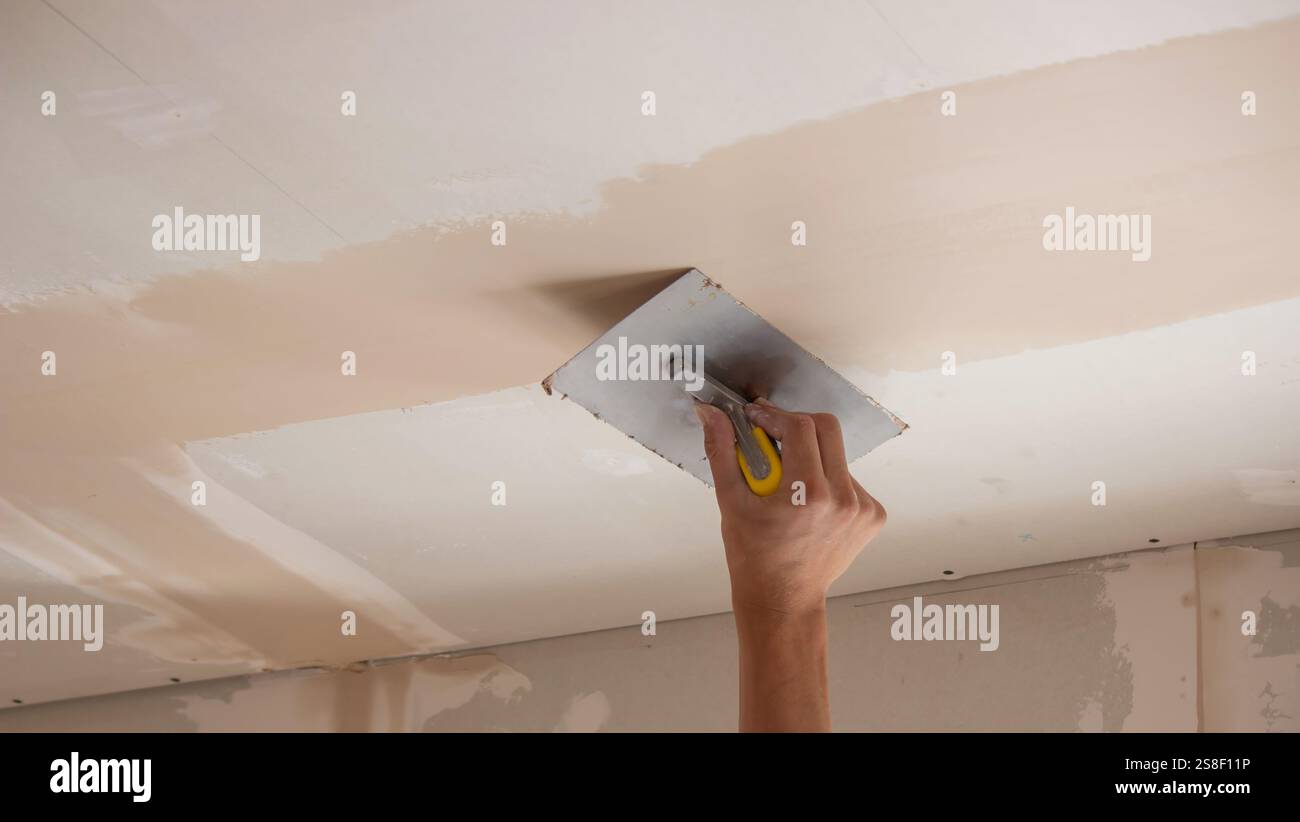 man plastering ceiling repair. Selective focus. Stock Photo