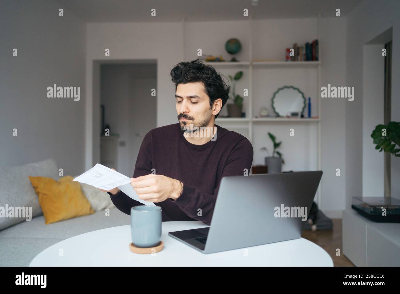 Young stressed looking handsome middle eastern man using computer and being overwhelmed by work. Stock Photo