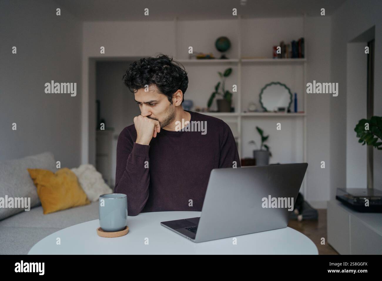Young stressed looking handsome middle eastern man using computer and being overwhelmed by work. Stock Photo