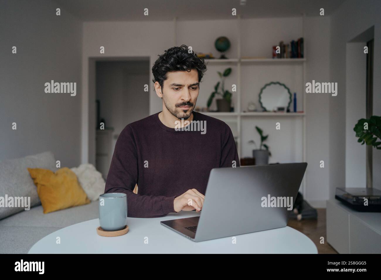 Young handsome middle eastern looking man using laptop computer in his home. Stock Photo
