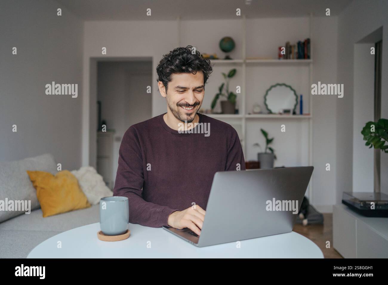 Young handsome middle eastern looking man using laptop computer in his home. Stock Photo