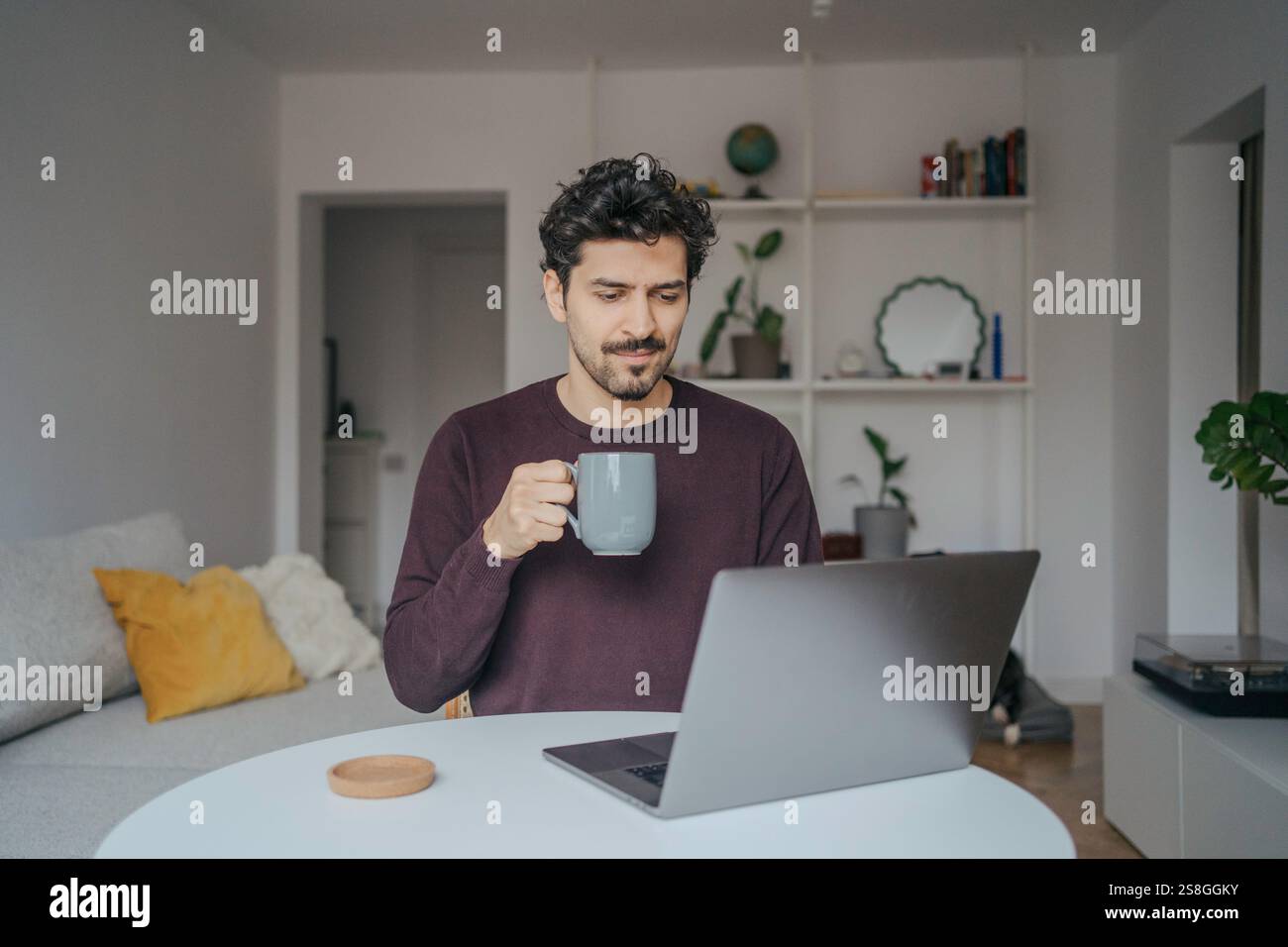 Young handsome middle eastern looking man using laptop computer in his home. Stock Photo