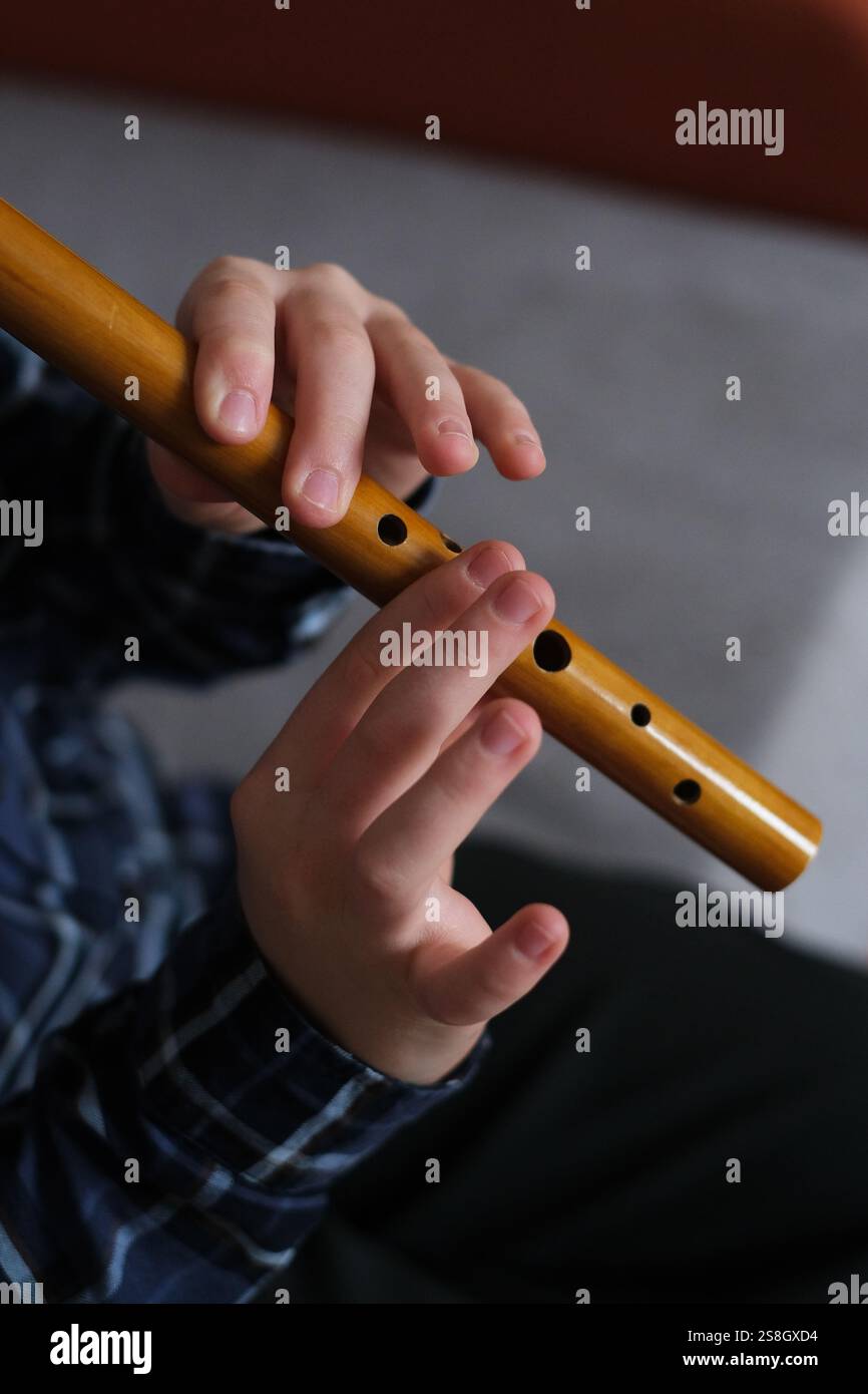 A child playing a wooden reed pipe, showcasing skill and concentration ...