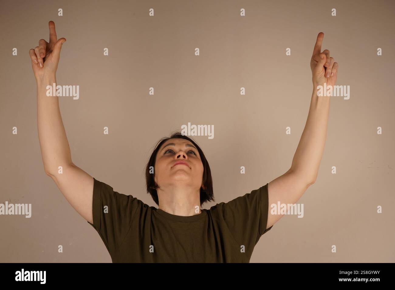 Hand Raises Close The woman looks straight up and raises her hands up with her index ...