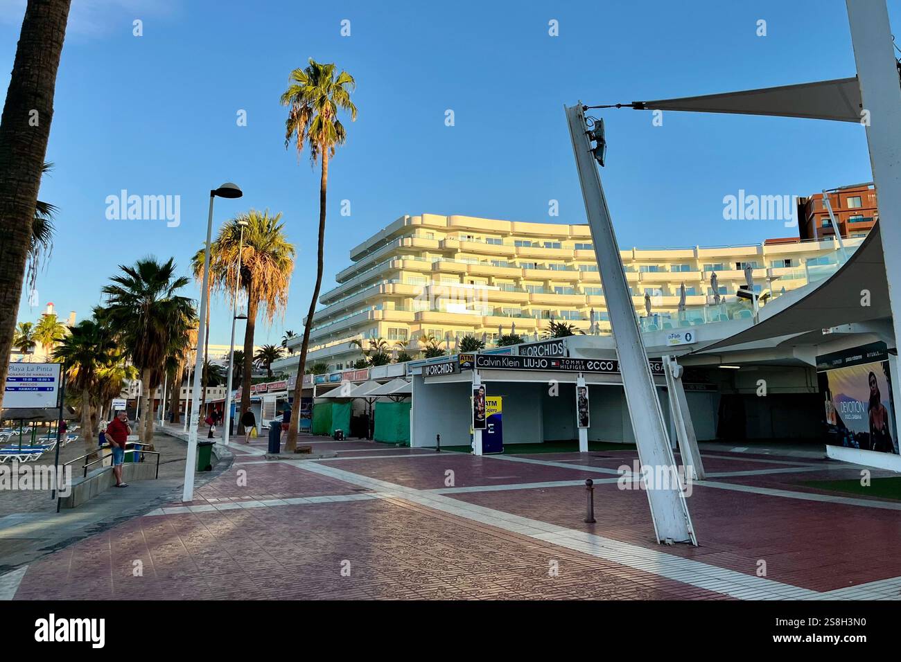 Looking towards the Hovima La Pinta Beachfront Family Hotel on the seafront promenade by Puerto Colon in Costa Adeje. 13th January 2025. - Smartphone Captured Stock Image