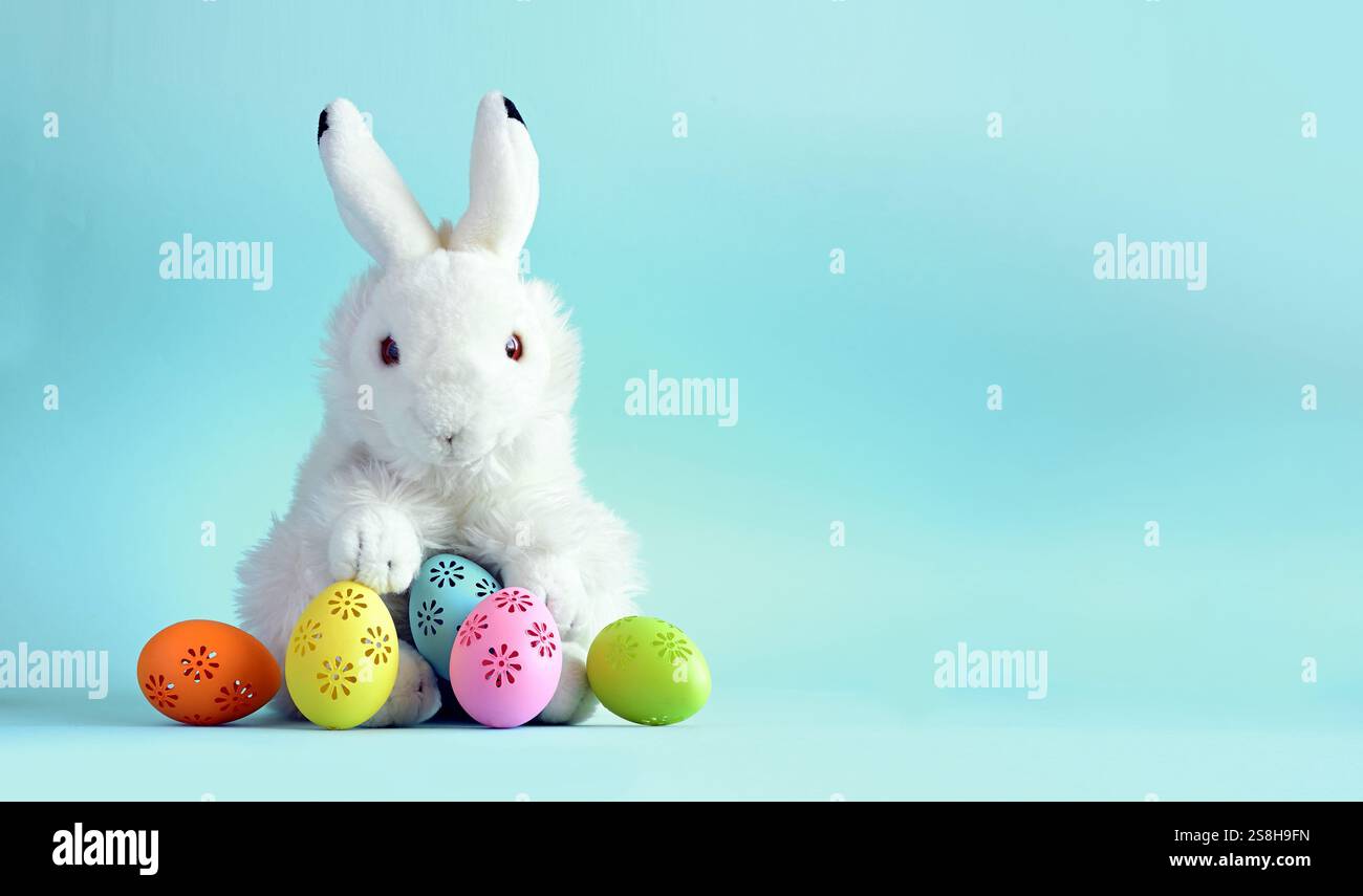 Easter bunny with colorful easter eggs on a blue background. Stock Photo