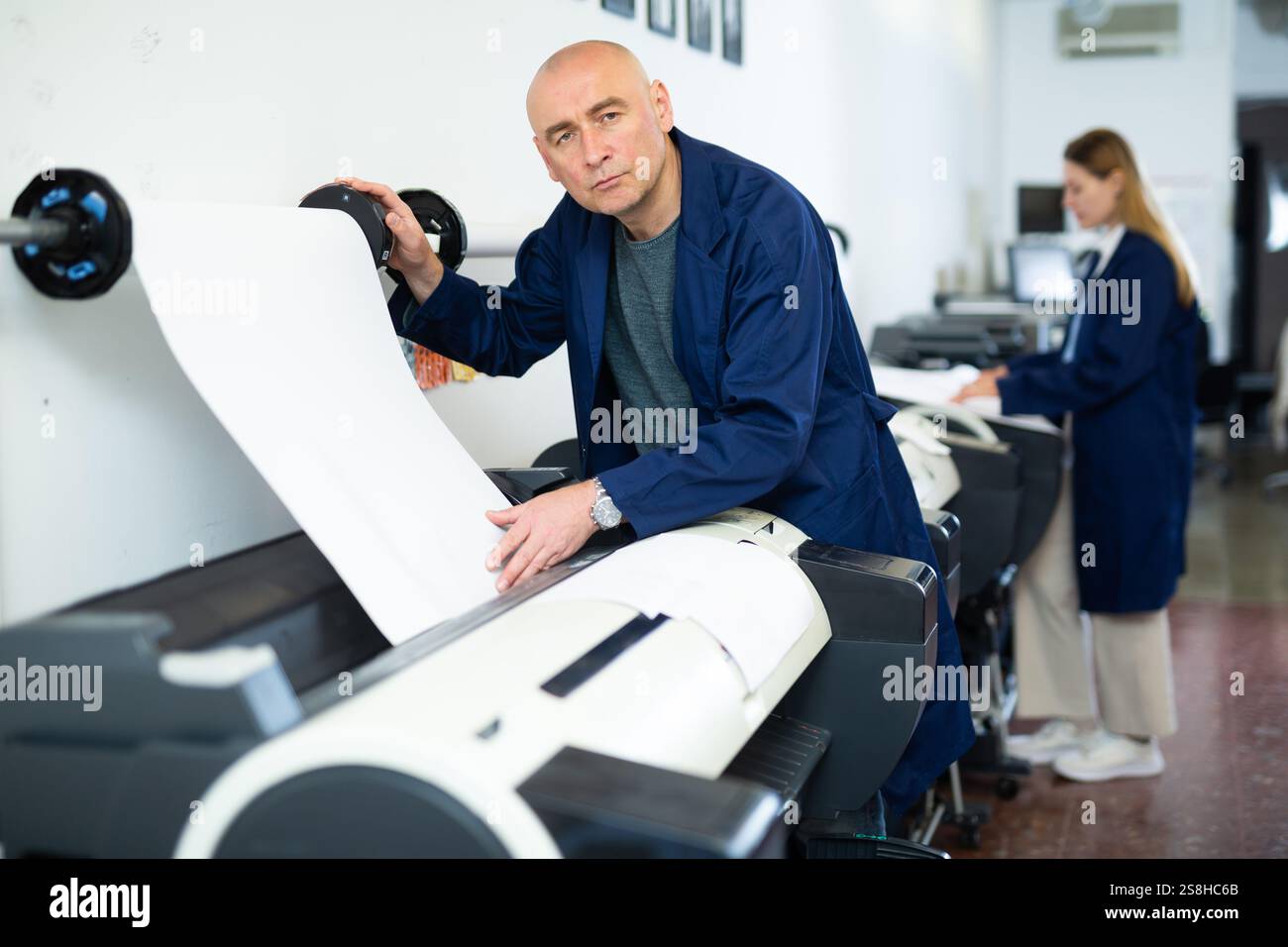 Service man uses plotter and checks functionality in printing shop Stock Photo