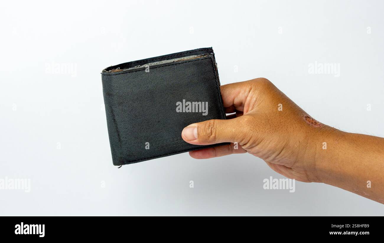 A tanned hand holding an ugly and broken wallet on a white background ...