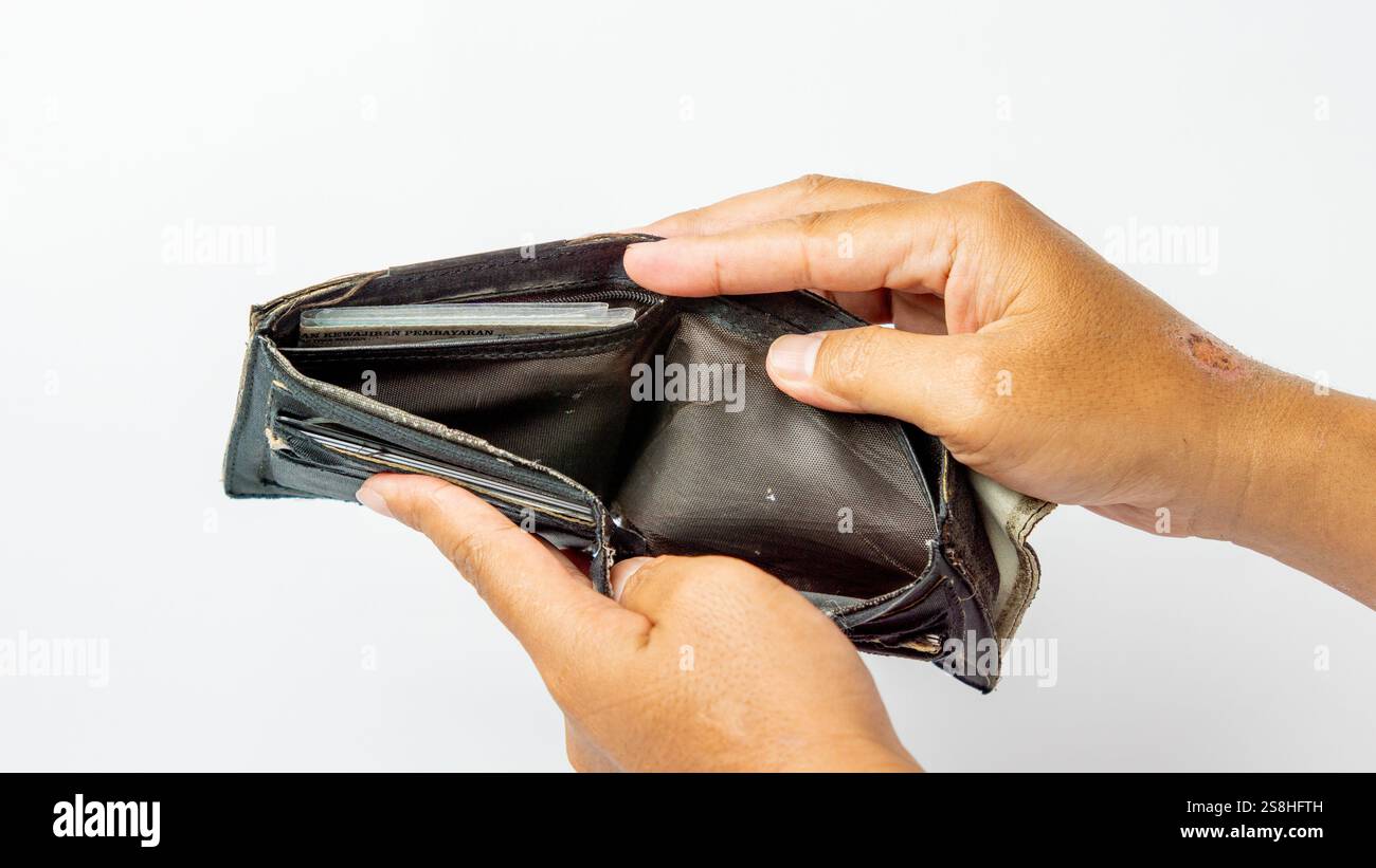 A tanned hand holding an ugly and broken wallet on a white background ...