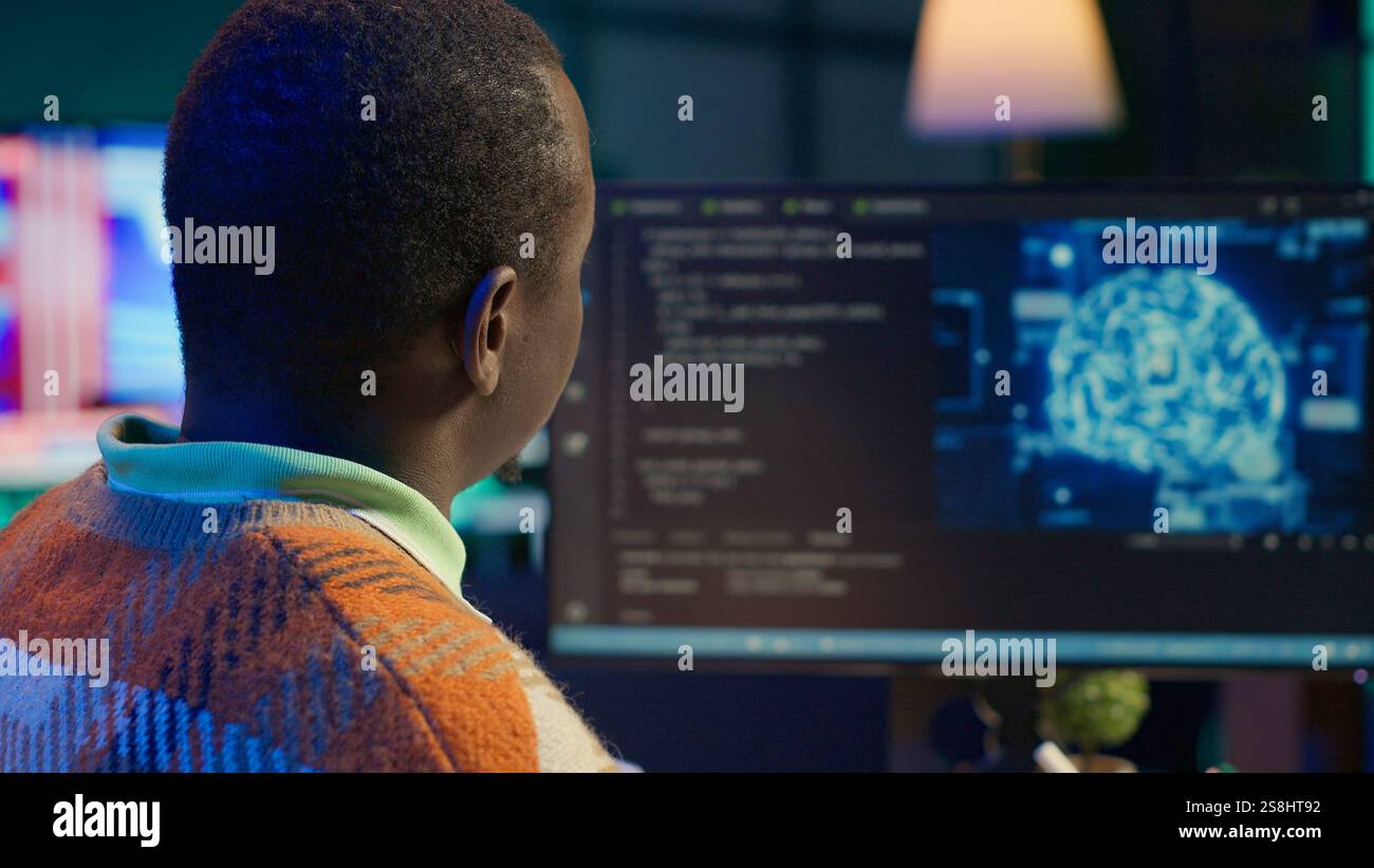 African american man working on computer to write code and programming in artificial intelligence and deep learning. Male IT engineer using pc to ensure cyber security, neural network. Camera A. Stock Photo