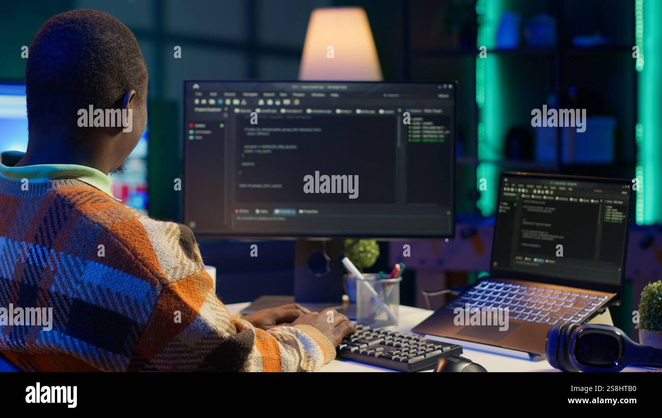 Black software engineer writes complex binary code scripts on computer, cybersecurity. Teleworking IT specialist in home office using programming language to safeguard consumer data. Camera A. Stock Photo