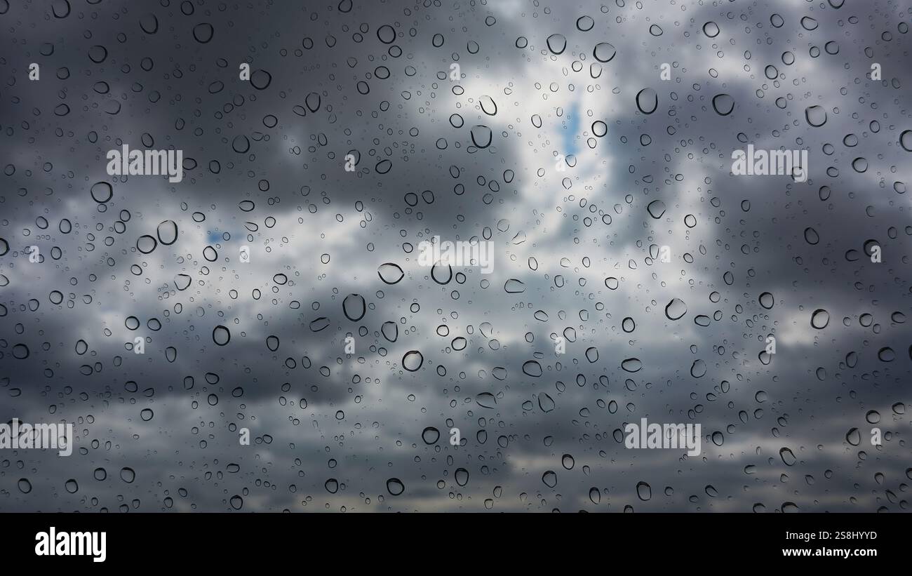 Focus on raindrops on window pane with storm clouds defocused beyond Stock Photo