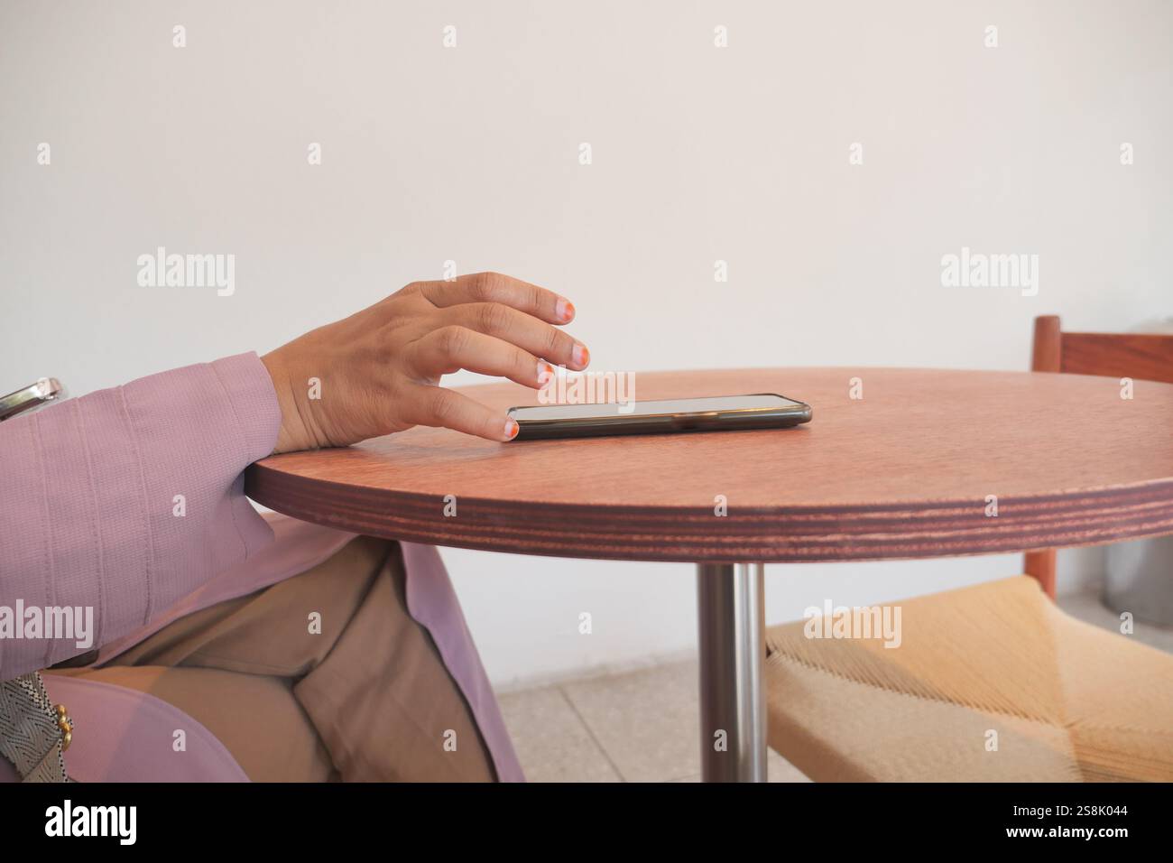A hand grabbing and picking up mobile phone on the table. Stock Photo