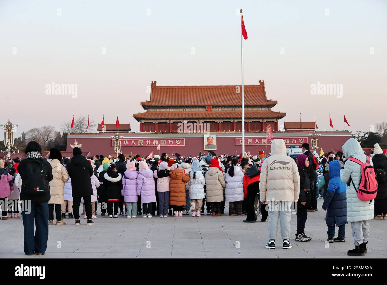 Tourists watch the flag raising ceremony at Tiananmen Square in Beijing
