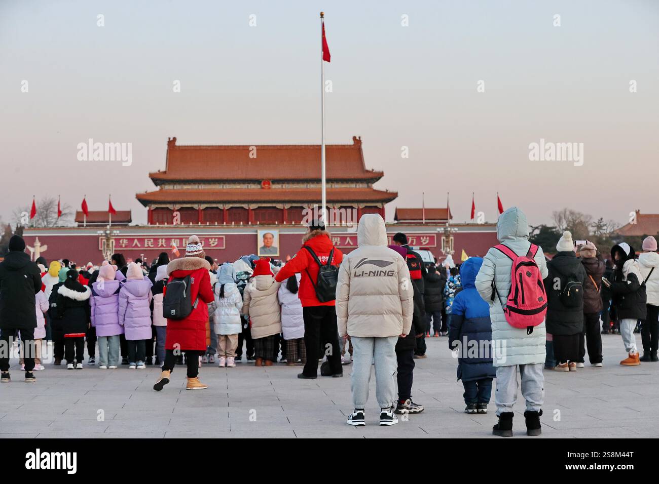 Tourists watch the flag raising ceremony at Tiananmen Square in Beijing