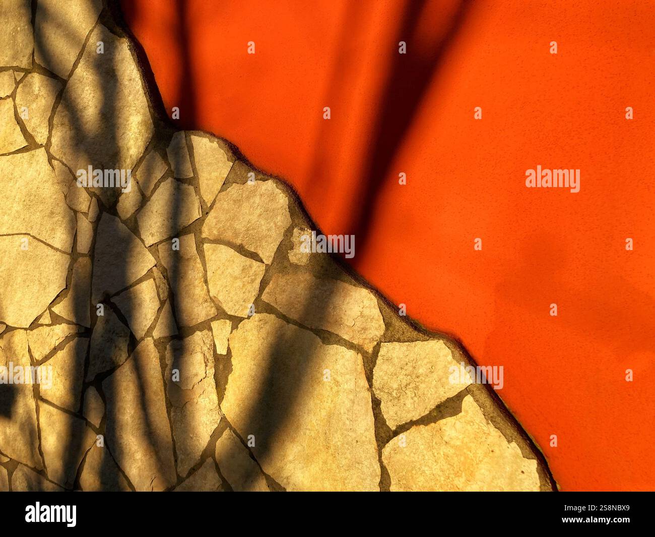 Contrasting textures in an artistic arrangement: stone patterns meet vibrant orange, enhanced by shadowplay. - Smartphone Captured Stock Image