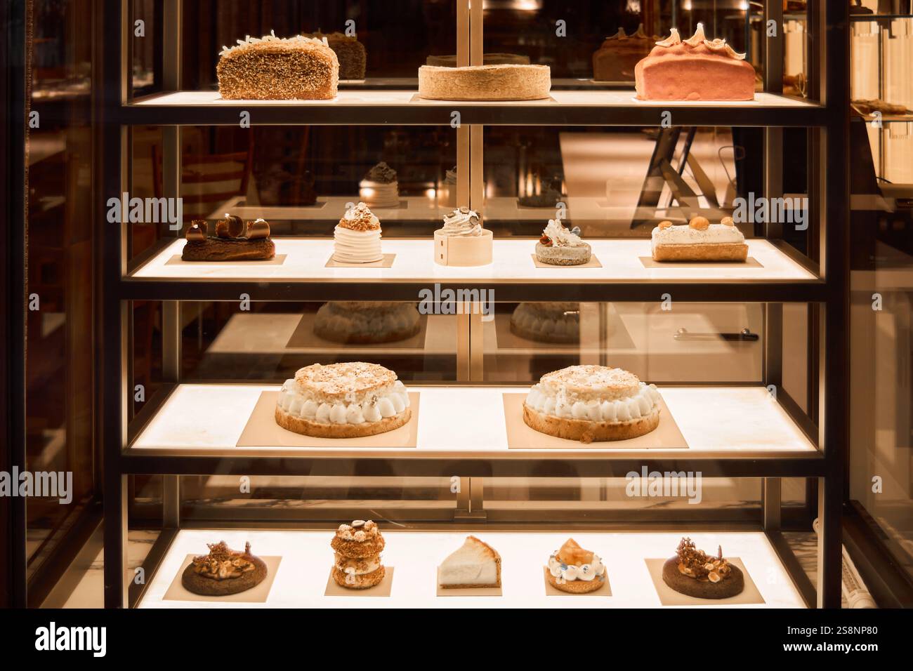 A beautiful display case filled with cakes and pastries, shining under bright lights, perfect for bakery advertisements and dessert showcases Stock Photo